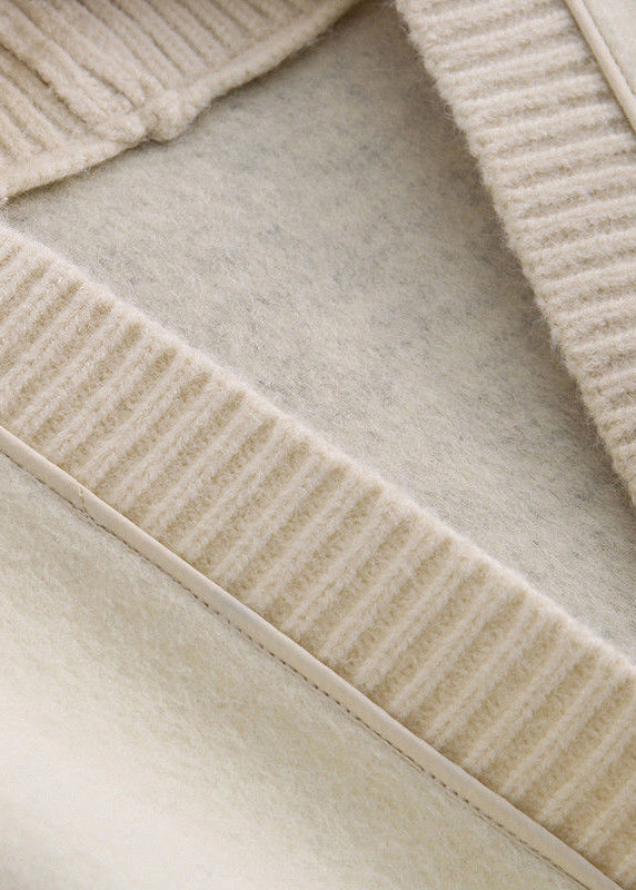 Luvik | Mustasta villasta valmistettu tilkkutakki napilla ja V-pääntiellä, pitkähihaisia