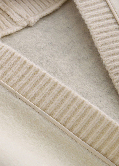 Luvik | Mustasta villasta valmistettu tilkkutakki napilla ja V-pääntiellä, pitkähihaisia