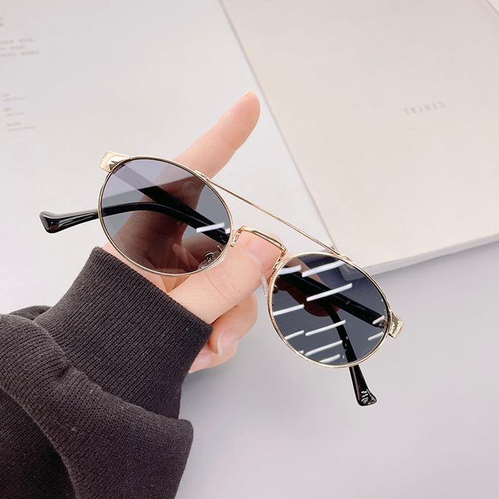 Dame moteriktig solbrille i stilfullt rundt design med gull aksenter Luvikno